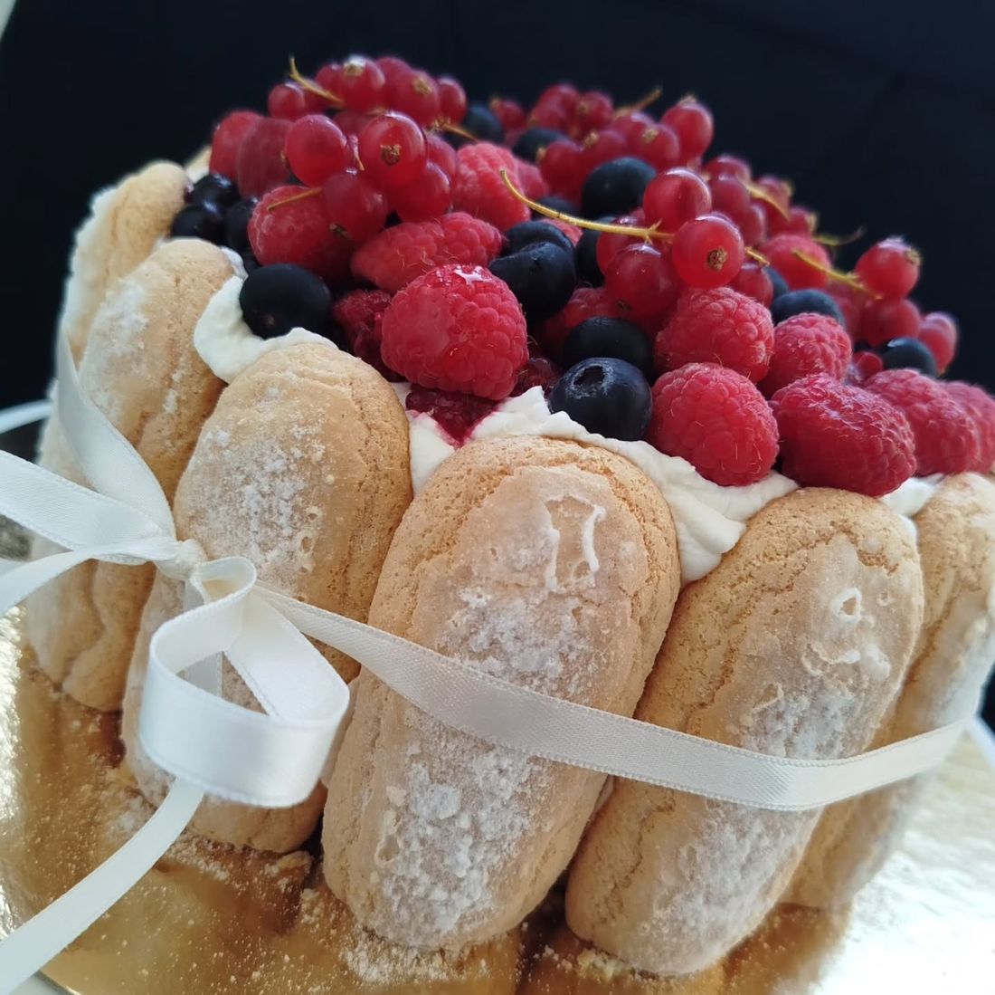 Charlotte aux biscuits cuillère et fruits rouges, nouée d'un ruban