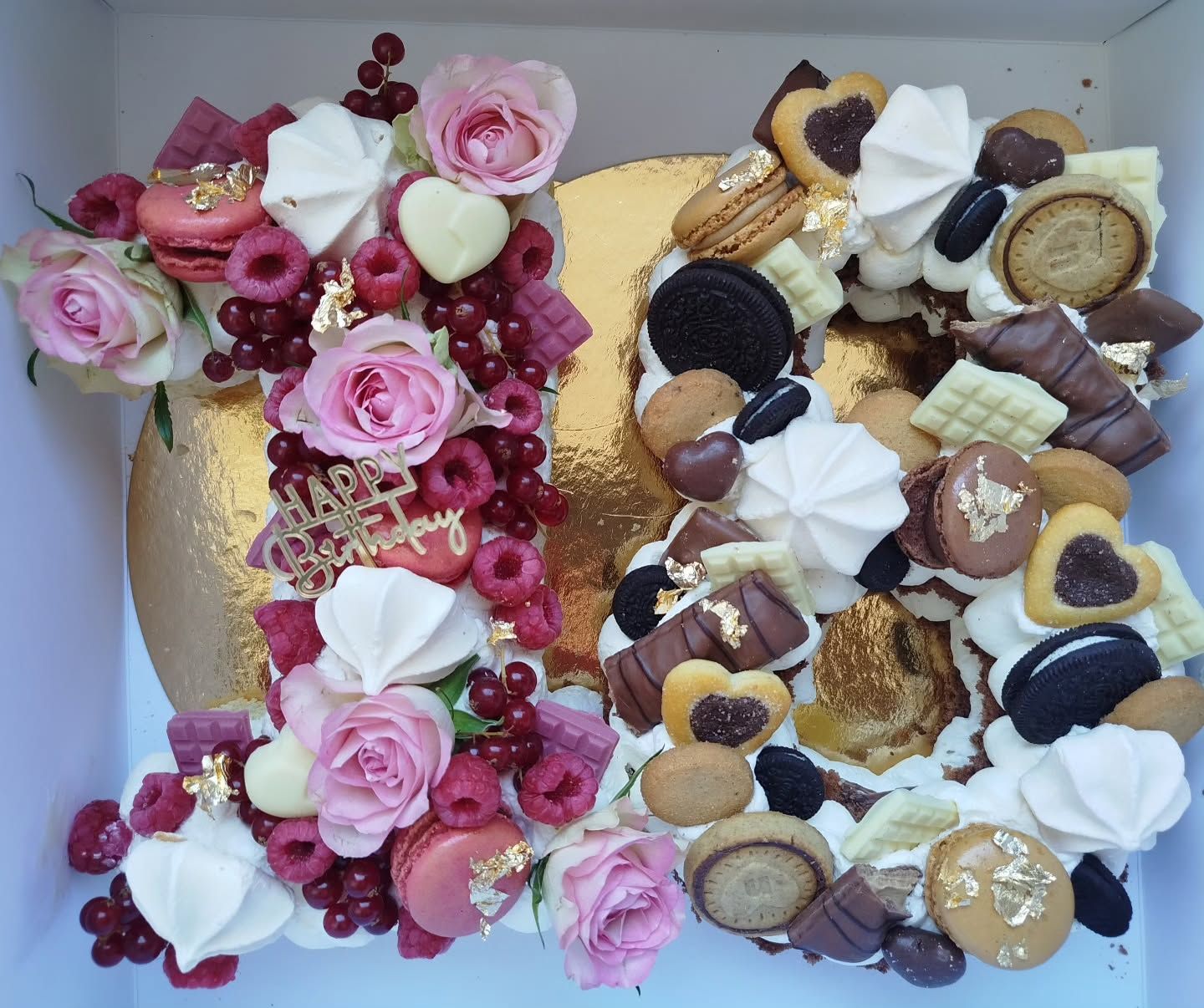 Number cake garni de roses, framboises, groseilles, macarons, meringues et chocolats sur plateau doré
