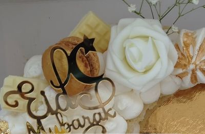 Gâteau décoré d'un topper Eid Mubarak, roses blanches et macarons dorés