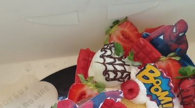 Gâteau garni de fraises, framboises et décor super-héros